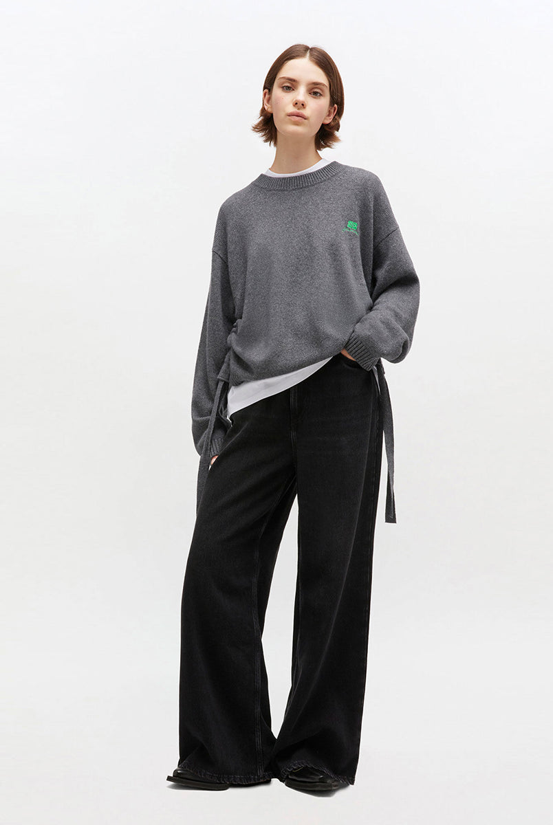 Szary, oversizowy sweter 2632 Charcoal Grey marki GANNI z okrągłym dekoltem i długimi rękawami. Posiada niewielkie logo marki na lewej piersi. Zakończony ściągaczami i wiązaniami u dołu. Wykonany z dzianiny z wełną. 