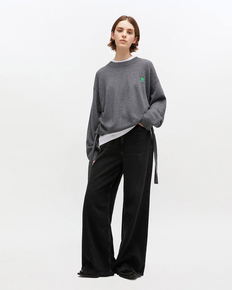 Szary, oversizowy sweter 2632 Charcoal Grey marki GANNI z okrągłym dekoltem i długimi rękawami. Posiada niewielkie logo marki na lewej piersi. Zakończony ściągaczami i wiązaniami u dołu. Wykonany z dzianiny z wełną. 