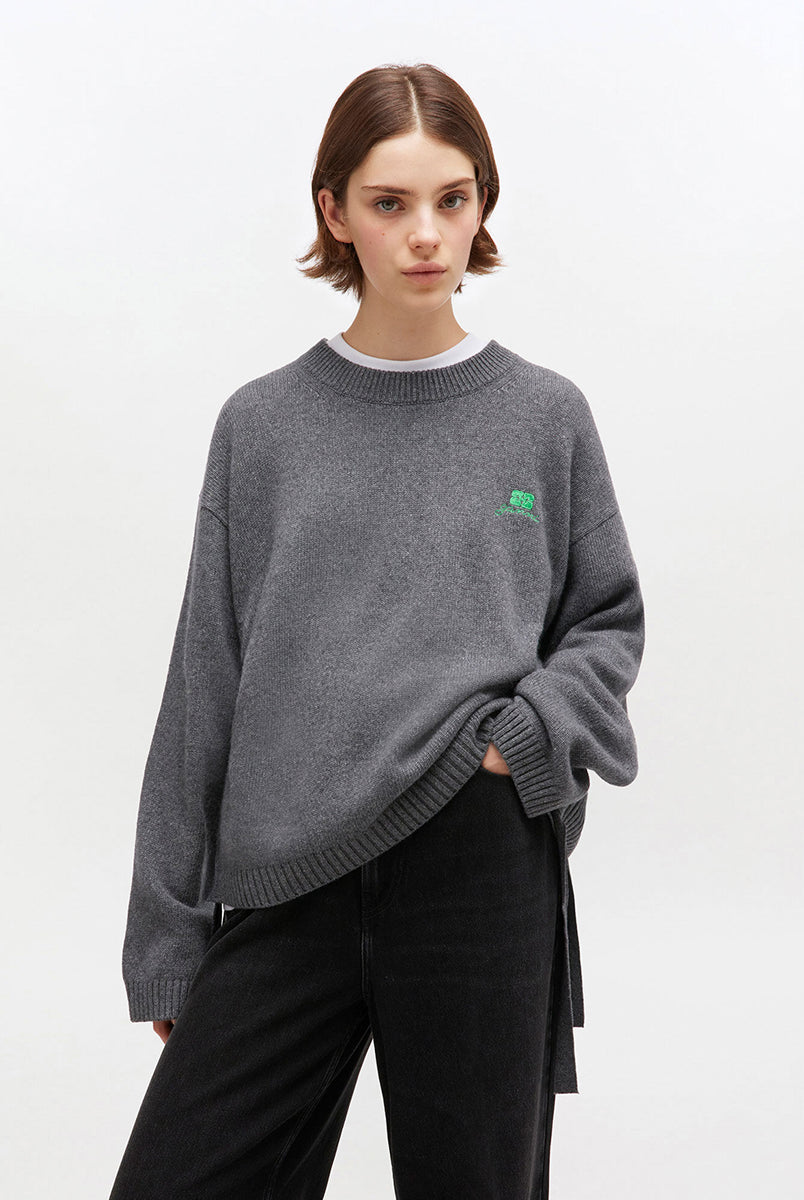 Szary, oversizowy sweter 2632 Charcoal Grey marki GANNI z okrągłym dekoltem i długimi rękawami. Posiada niewielkie logo marki na lewej piersi. Zakończony ściągaczami i wiązaniami u dołu. Wykonany z dzianiny z wełną. 