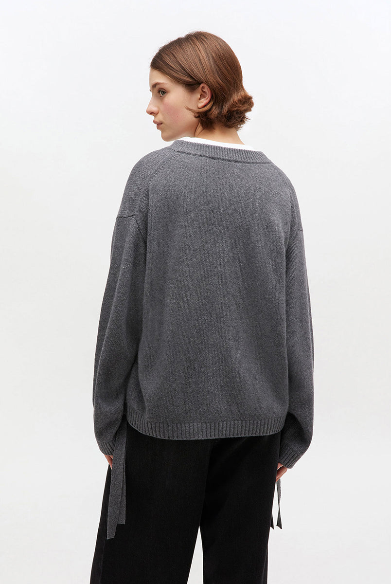 Szary, oversizowy sweter 2632 Charcoal Grey marki GANNI z okrągłym dekoltem i długimi rękawami. Posiada niewielkie logo marki na lewej piersi. Zakończony ściągaczami i wiązaniami u dołu. Wykonany z dzianiny z wełną. 