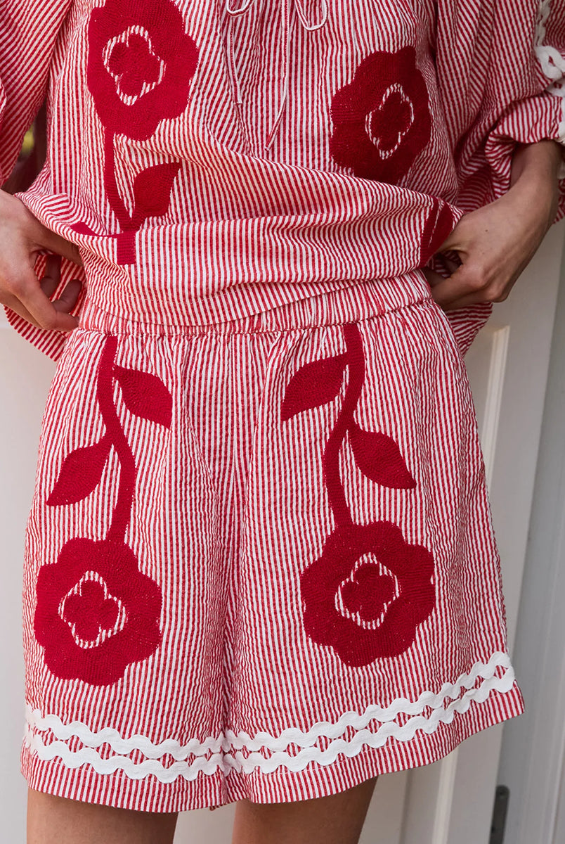 Luźne szorty o swobodnym kroju Abelone Red Flower marki SISSEL EDELBO z gumką w pasie i kieszeniami w bocznych szwach. Ozdobione są pięknym, wyrazistym haftem kwiatowym oraz szerokimi, zygzakowatymi taśmami u dołu. Wykonane są z jakościowej bawełny organicznej.
-Luźny, swobodny krój
-Piękny haft kwiatowy
-Zamów szorty w swoim standardowym rozmiarze