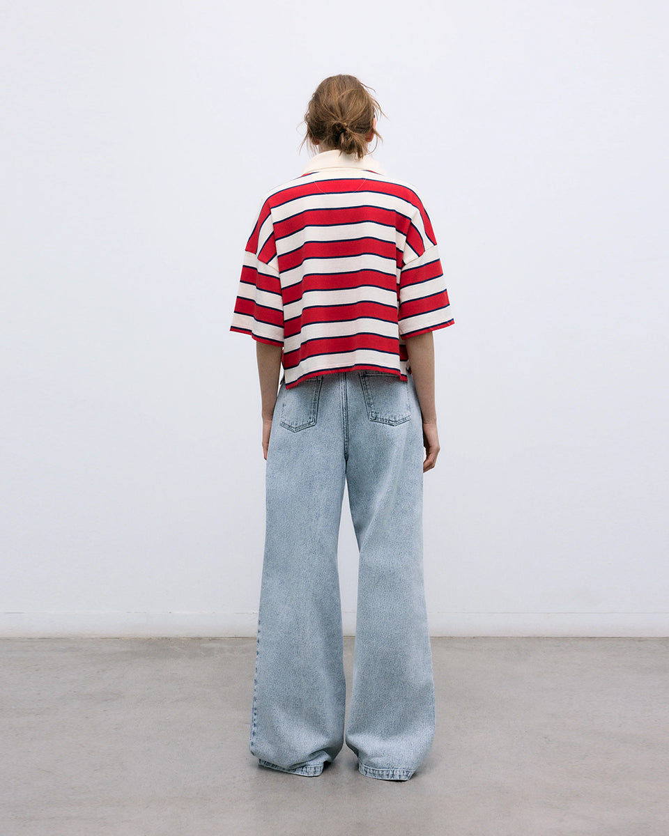 Krótki, pudełkowy t-shirt polo Acacia Polo Tulip Red z kontrastowymi paskami. Posiada kołnierzyk, opadające ramiona i krótki, szeroki rękaw o długości do łokci. Pod szyją zapinany na guziki. Nad lewą piersią posiada niewielką naszywkę z logo marki. Wykonany z bawełny.
-Luźny fason
-100% bawełna
-Zamów w swoim standardowym rozmiarze