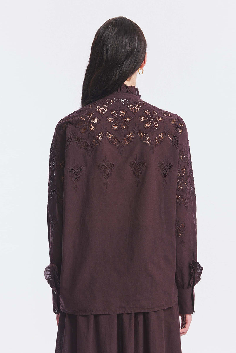 Haftowana, bawełniana bluzka Albertine Antik Batik Burgundy z długimi rękawami i niewielką stójką, która wykończona jest falbanką. Posiada ażurowy haft z przodu i na rękawach. Ma kryte zapięcie na guziki. Ta zwiewna bluzka, inspirowana modą wiktoriańską może być noszona samodzielnie lub w komplecie z pasującą spódnicą, tworząc romantyczną stylizację. 