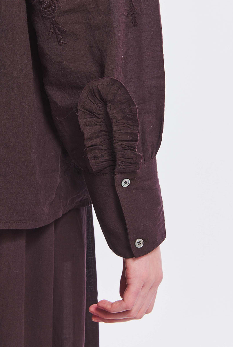Haftowana, bawełniana bluzka Albertine Antik Batik Burgundy z długimi rękawami i niewielką stójką, która wykończona jest falbanką. Posiada ażurowy haft z przodu i na rękawach. Ma kryte zapięcie na guziki. Ta zwiewna bluzka, inspirowana modą wiktoriańską może być noszona samodzielnie lub w komplecie z pasującą spódnicą, tworząc romantyczną stylizację. 