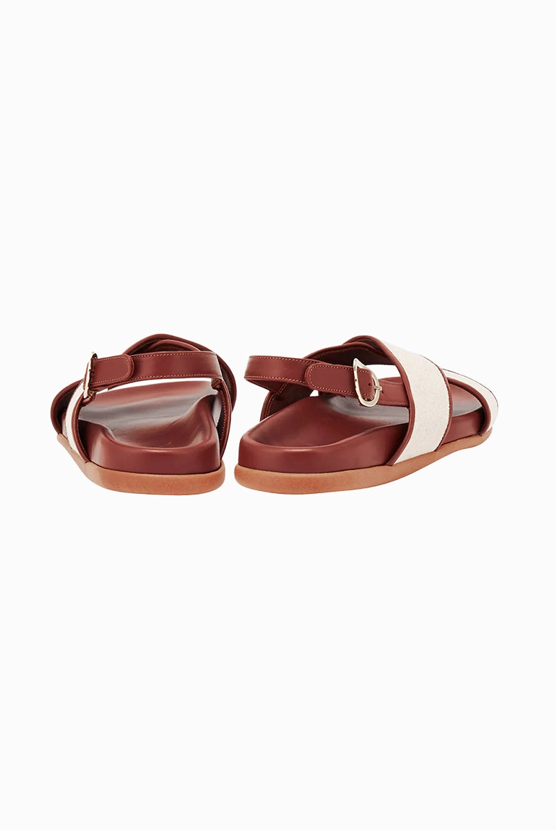 Skórzane sandały Ikesia Ancient Greek Sandals na płaskiej, profilowanej od wewnętrznej strony podeszwie z szerokimi, skrzyżowanymi paskami na górze obszytymi naturalną, płócienną tkaniną.