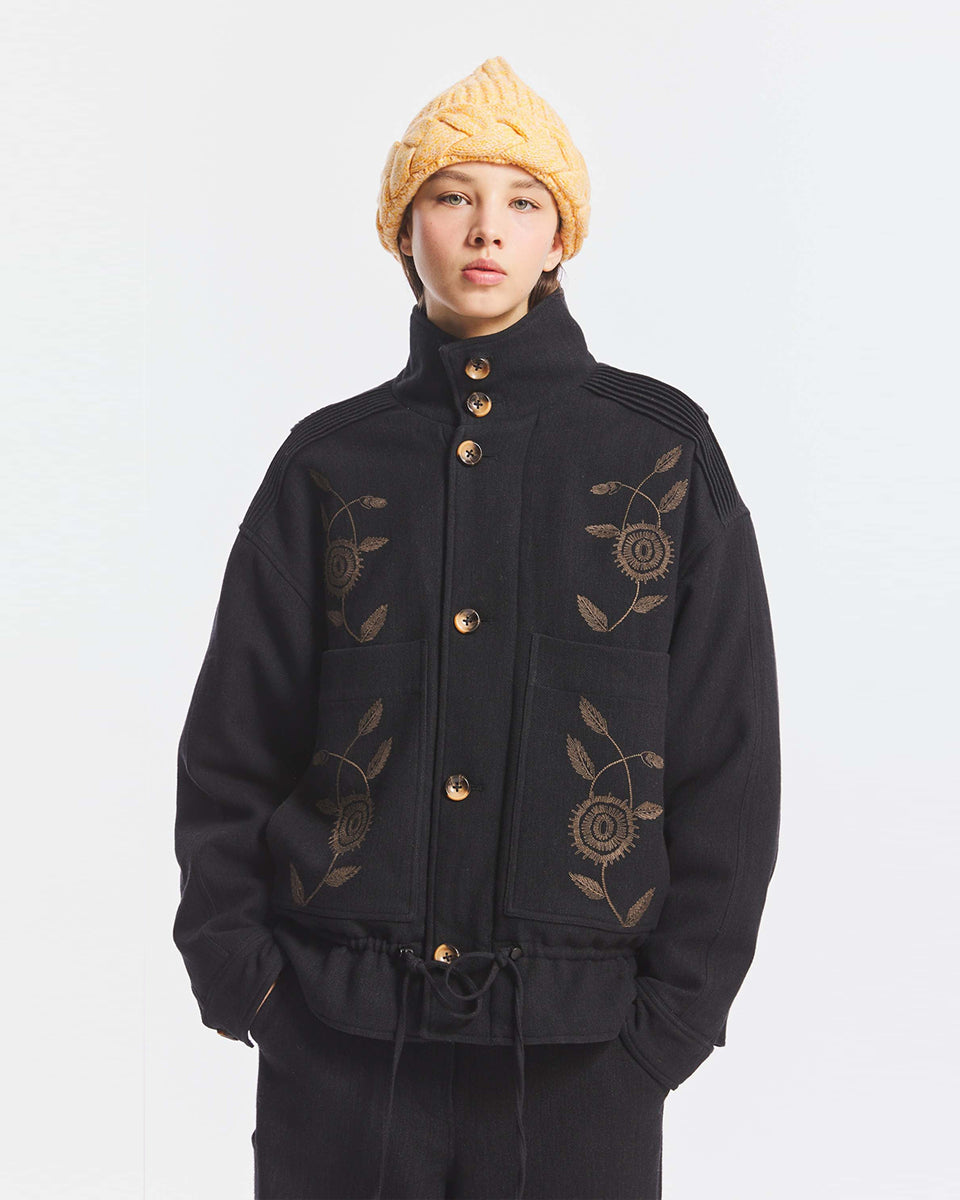Kurtka o kroju oversize Aristide Antik Batik Grey z wysokim kołnierzem i zapięciem na guziki. Wykonana z mieszanki bawełny, wełny i nylonu. Model ten wyróżnia się strukturalną formą i swobodnym ułożeniem na sylwetce. Przód zdobią delikatne, kwiatowe hafty, które nadają kurtce fakturę i charakter. Posiada dwie naszywane kieszenie i dwie kieszenie boczne. Regulowany u dołu sznurek pozwala na dowolne podkreślenie sylwetki. Model wykończony podszewką z lyocellu. 