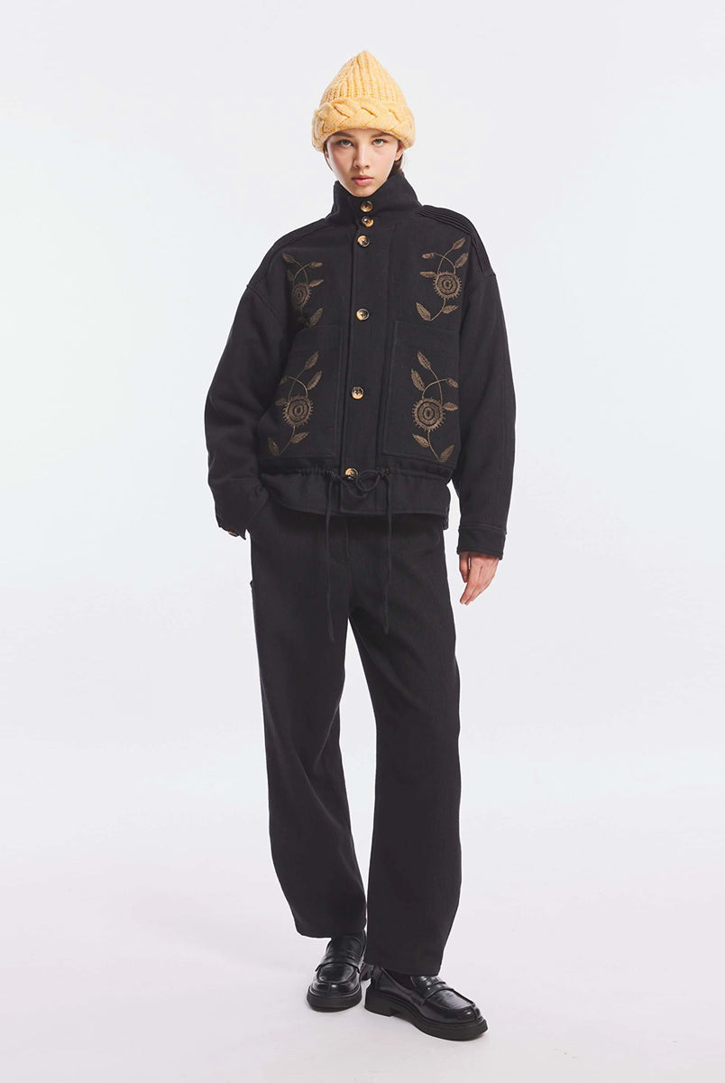 Kurtka o kroju oversize Aristide Antik Batik Grey z wysokim kołnierzem i zapięciem na guziki. Wykonana z mieszanki bawełny, wełny i nylonu. Model ten wyróżnia się strukturalną formą i swobodnym ułożeniem na sylwetce. Przód zdobią delikatne, kwiatowe hafty, które nadają kurtce fakturę i charakter. Posiada dwie naszywane kieszenie i dwie kieszenie boczne. Regulowany u dołu sznurek pozwala na dowolne podkreślenie sylwetki. Model wykończony podszewką z lyocellu. 