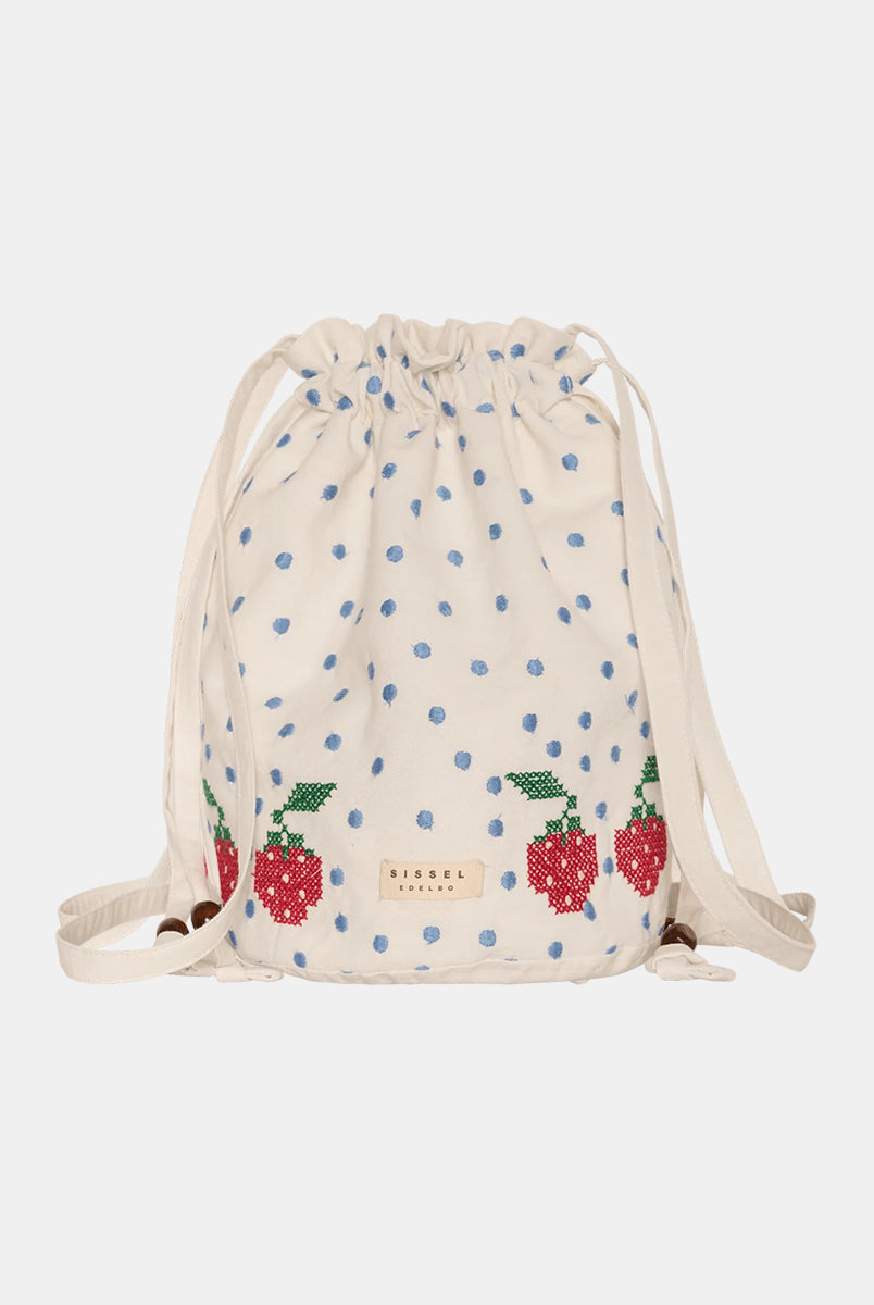 Torebka na ramię Babba Drawstring Off White marki SISSEL EDELBO z bawełny organicznej. Zmieścisz w niej niezbędne rzeczy na co dzień. Ma okrągłe dno i można ją zamknąć za pomocą sznurków. Ozdobiona jest uroczymi, niebieskimi kropkami i haftem krzyżykowym wzdłuż dolnej krawędzi, a także małym, haftowanym napisem SE.