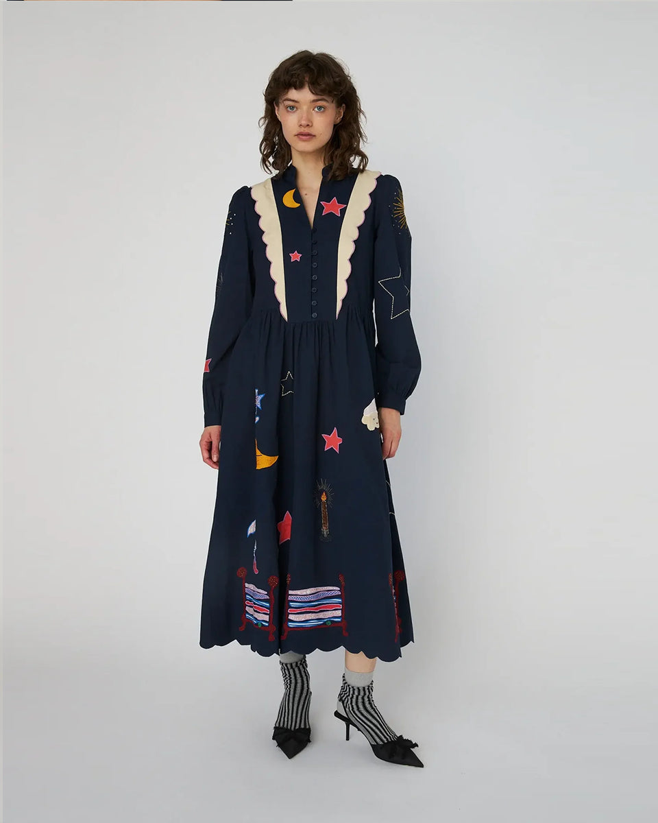 Bawełniana sukienka midi Bead Embellished Navy z uroczymi ręcznie haftowanymi motywami MIDNIGHT. Posiada dekolt w serek z zapięciem na guziki i długie, lekko bufiaste rękawy. Sukienka jest zwężana i przylegająca w talii, co pięknie podkreśla sylwetkę. Ma długość do połowy łydki. U dołu wykończona muszelkowo. 