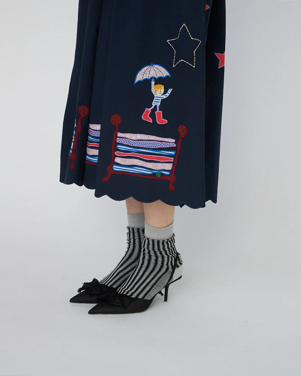 Bawełniana sukienka midi Bead Embellished Navy z uroczymi ręcznie haftowanymi motywami MIDNIGHT. Posiada dekolt w serek z zapięciem na guziki i długie, lekko bufiaste rękawy. Sukienka jest zwężana i przylegająca w talii, co pięknie podkreśla sylwetkę. Ma długość do połowy łydki. U dołu wykończona muszelkowo. 