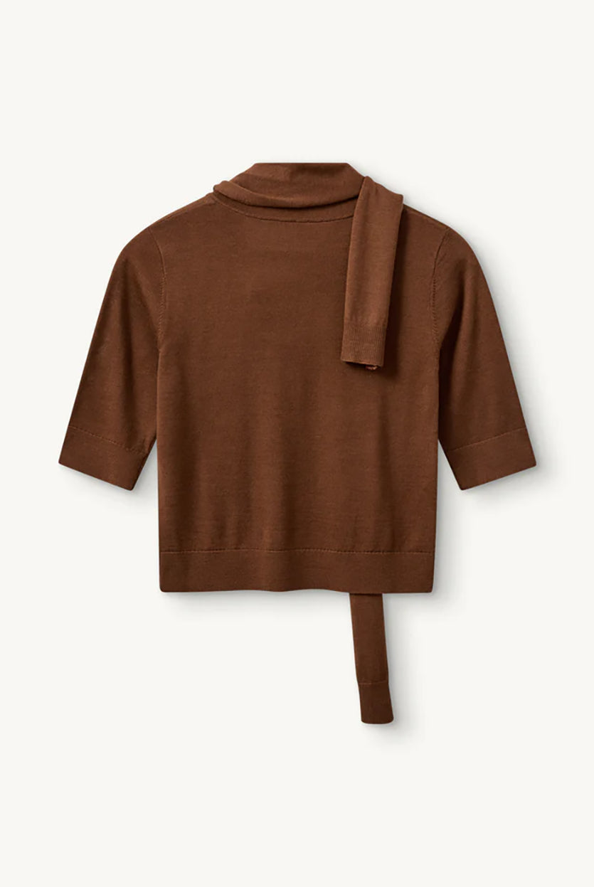 Cienki, brązowy sweter Bergen Scarf Cinnamon o dopasowanym kroju, z elastycznym ściagaczem w pasie i przy zakończeniach rękawów. Rękawy są długości do łokcia. Dekolt jest w nieco głębszy i okrągły z doszytym długim szalem, który można puścić luźno lub dowolnie związać. Wykonany w 100% z wełny merino.