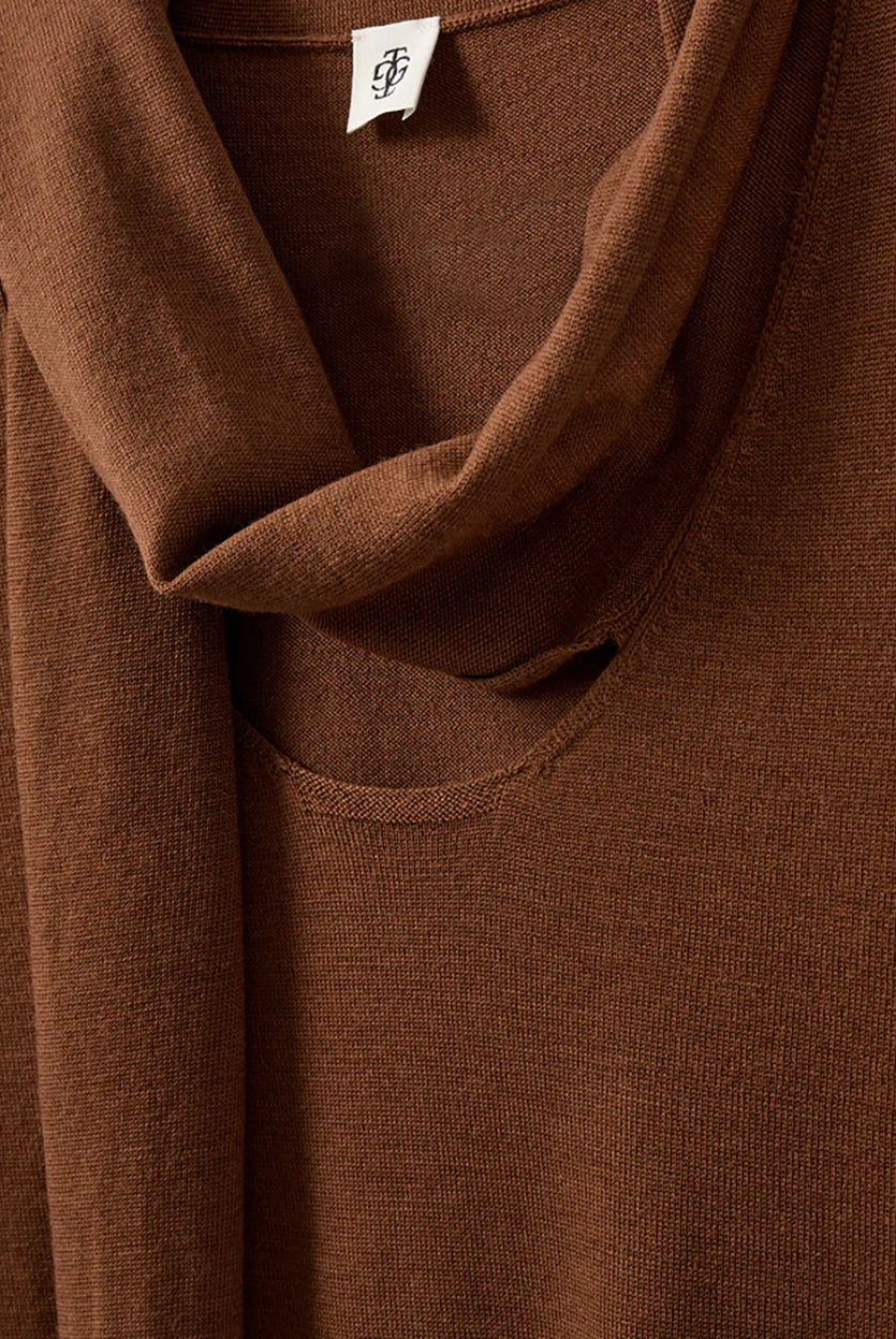 Cienki, brązowy sweter Bergen Scarf Cinnamon o dopasowanym kroju, z elastycznym ściagaczem w pasie i przy zakończeniach rękawów. Rękawy są długości do łokcia. Dekolt jest w nieco głębszy i okrągły z doszytym długim szalem, który można puścić luźno lub dowolnie związać. Wykonany w 100% z wełny merino.