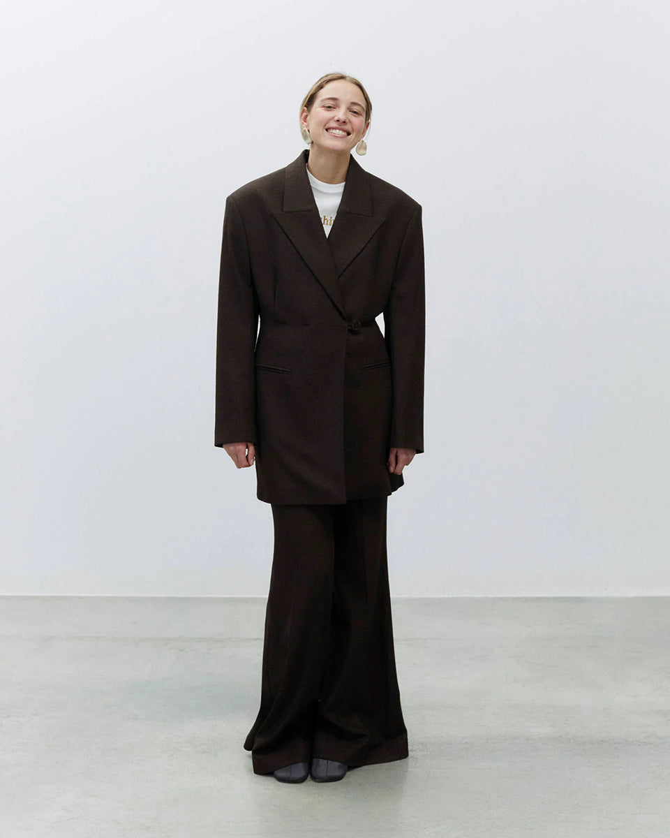 Bardzo długa, jednorzędowa marynarka Oversized Flannel Choco z wyraźnie zaznaczonymi ramionami i zwężeniem w talii. Ma asymetryczne zapięcie na guzik oraz kieszenie wpuszczane z przodu. Wykonana z mieszanki wełny i wiskozy. 