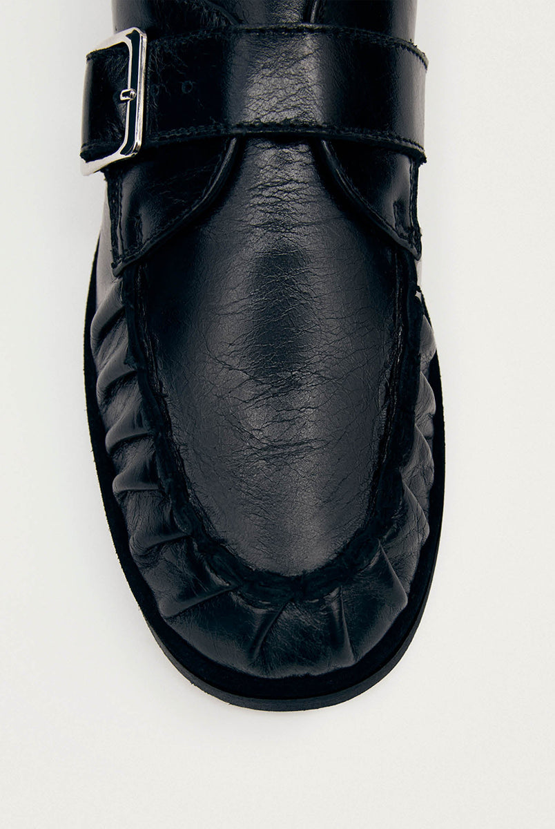 Czarne mokasyny Alohas Brandy Black Leather Loafers ze srebrną klamrą, która dodaje elegancji. Model charakteryzuje się unikatowym, marszczonym wykończeniem na nosku. Wykonane z wysokiej jakości skóry. Idealnie łączą ponadczasowy design z nowoczesnymi detalami.
