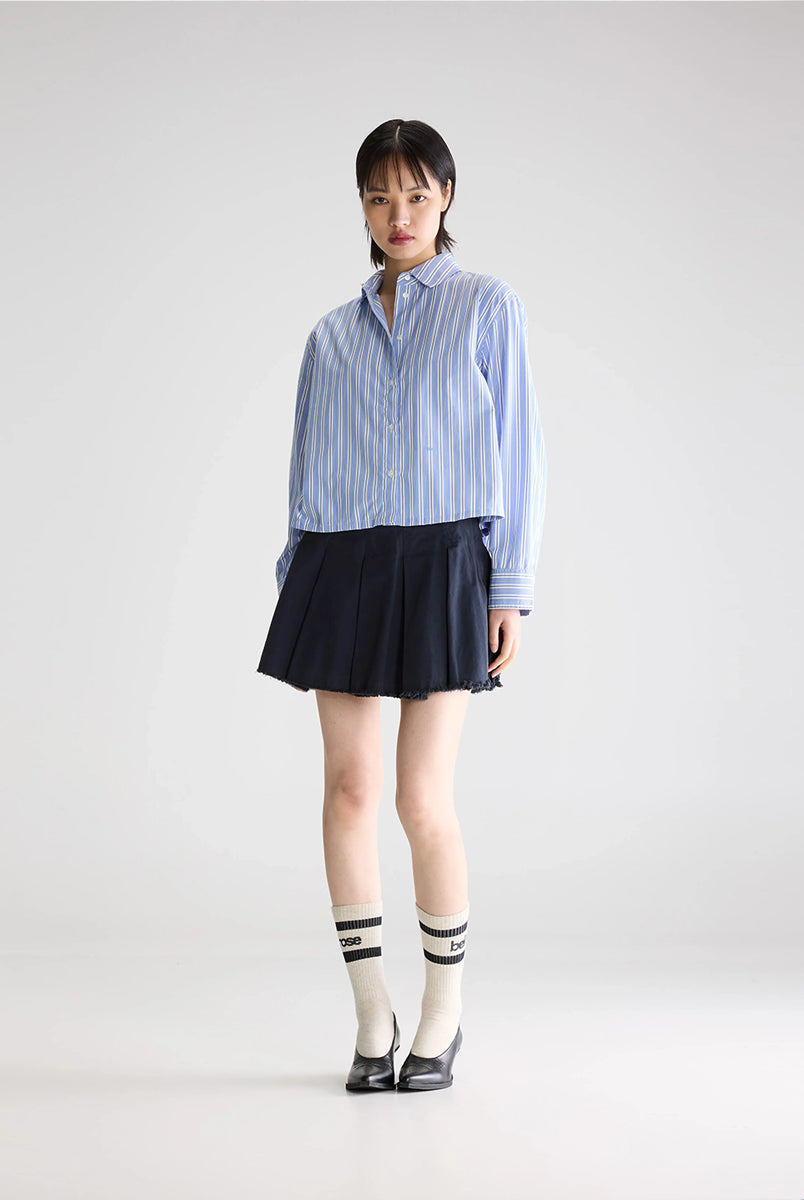 Luźna, krótka koszula Capri Stripe A marki BELLEROSE w niebieskie paski. Posiada klasyczny kołnierzyk oraz długie rękawy zakończone mankietami zapinanymi na guzik. Wykonana w 100% z bawełny. Z przodu przy guzikach ma wyhaftowane małe logo marki. Zapinana na guziki. Ma lekko skrócony fason.
-Zamów koszulę w swoim standardowym rozmiarze