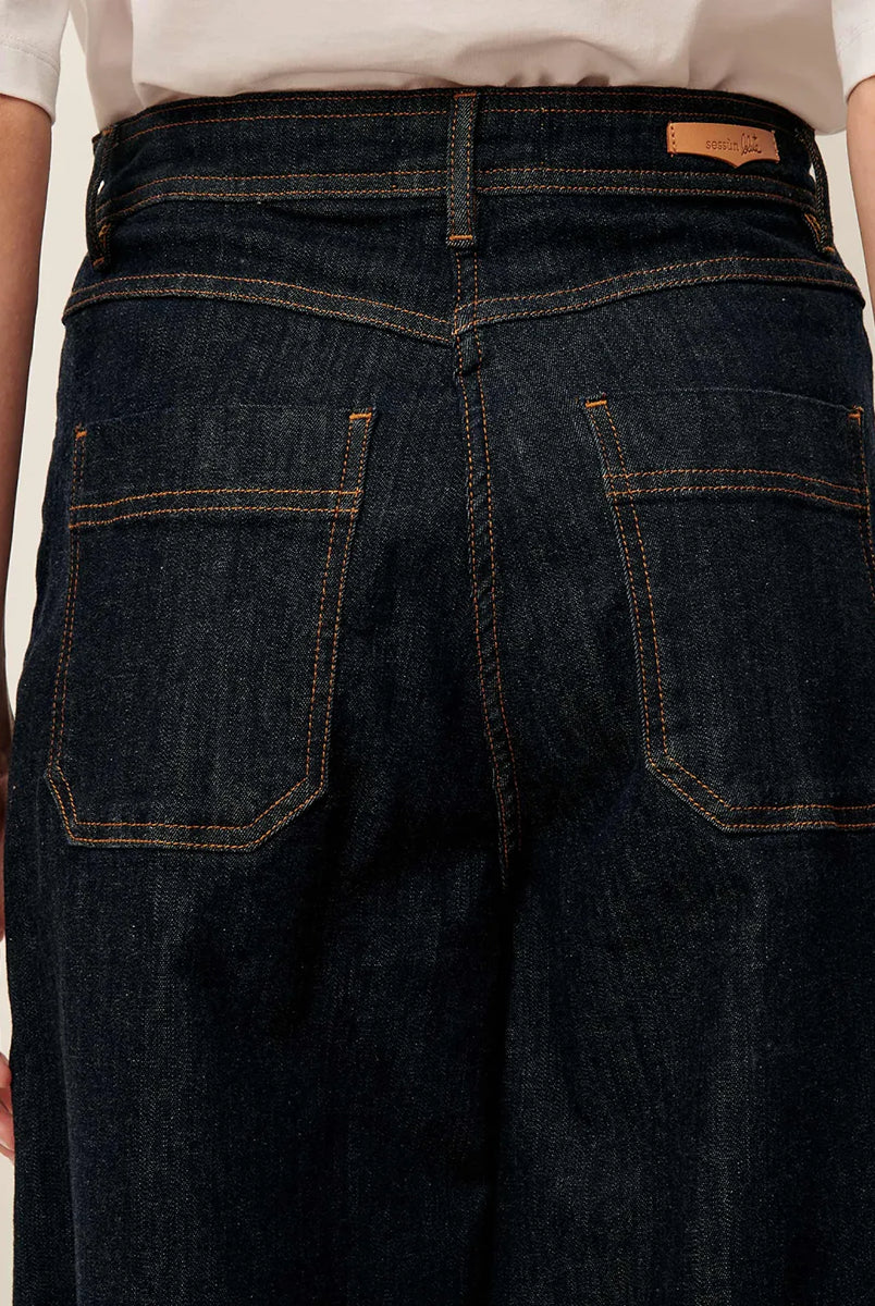 Ciemne Jeansy Captain Denim Rince z wysokim stanem i szerokimi nogawkami wykonane z denimu stonewash. Zapinane na guzik i kryty zamek błyskawiczny. Mają kieszenie z przodu oraz z tyłu i wytłoczoną, skórzaną naszywkę z logo marki.