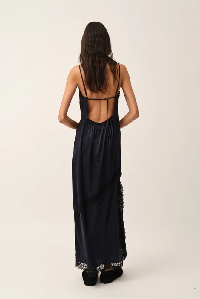 Elegancka, lejąca sukienka maxi na cienkich, regulowanych ramiączkach Cata Lace The Garment wykończona zmysłową koronką. Posiada prosty dekolt i głębokie wycięcie na plecach. Z przodu dekorowana asymetryczną koronką. Sukienka ma boczne rozcięcie oraz długość do kostek. Z tyłu delikatnie drapowana. Wykonana z jedwabnej, śliskiej tkaniny.