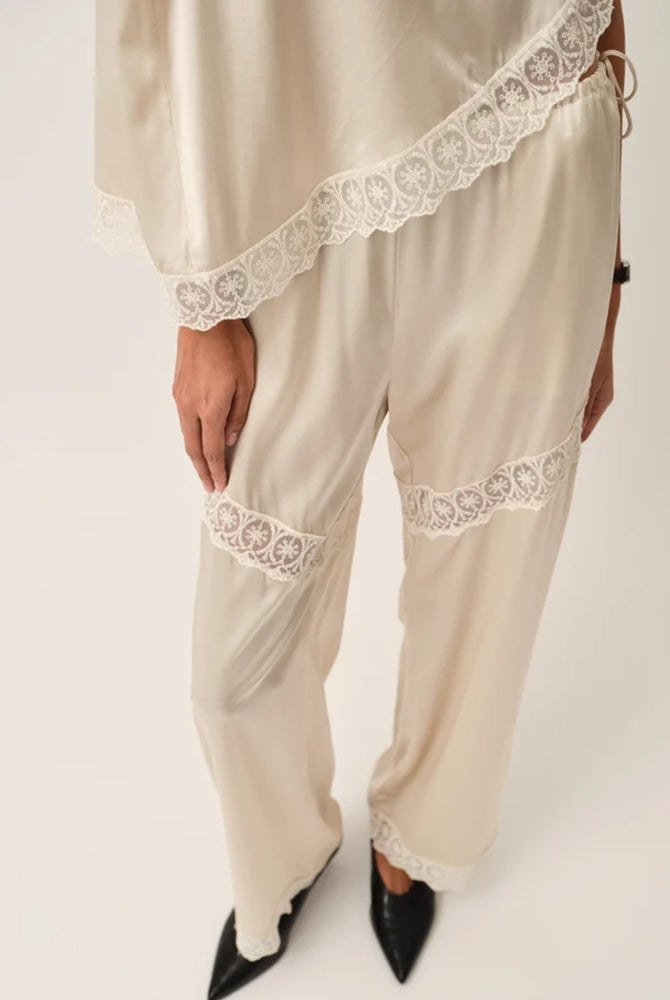 Lejące, jedwabne spodnie Cata Lace The Garment ze średnim stanem i prostą, luźną nogawką. Wiązane na bokach bioder. Wykończone zmysłową koronką.