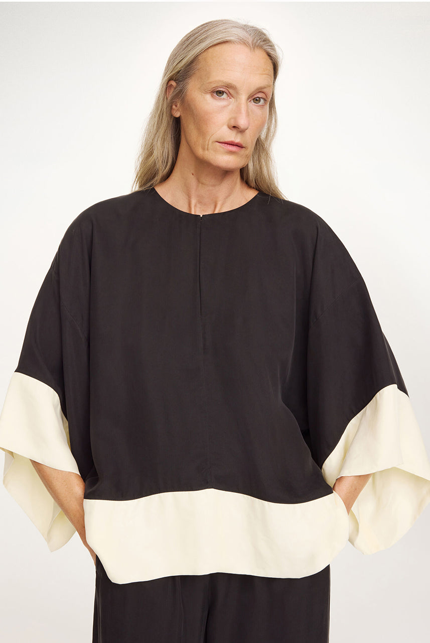 Elegancka, luźna bluzka Cicie Black White By Malene Birger o kwadratowym kroju, z głębokim dekoltem z zapięciem i szerokimi, krótkimi rękawami. Zapinana na haftkę i zatrzask. Wykonana z przewiewnej i gładkiej mieszanki cupro. Bluzka będzie idealną częścią stylizacji na eleganckie, wieczorne wyjścia.
-Luźny, kwadratowy krój
-Głęboki dekolt z zapięciem
-Zamów bluzkę w swoim standardowym rozmiarze