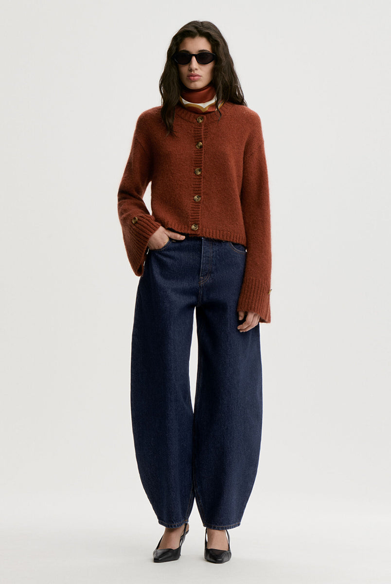 Krótki, swobodnie układający się sweter Cierrou Soft By Malene Birger Spiced Berry w rudym odcieniu. Ma okrągły dekolt i długie, lekko rozszerzane rękawy. Zapinany na rząd guzików. Dodatkowe, mniejsze guziki umieszczono również jako subtelny akcent na mankietach rękawów. Wykończony ściągaczami. Wykonany z ciepłej mieszanki wełny i moheru.
-Rozszerzane rękawy
-Dzianina z wełną i moherem
-Zamów sweter w swoim standardowym rozmiarze 