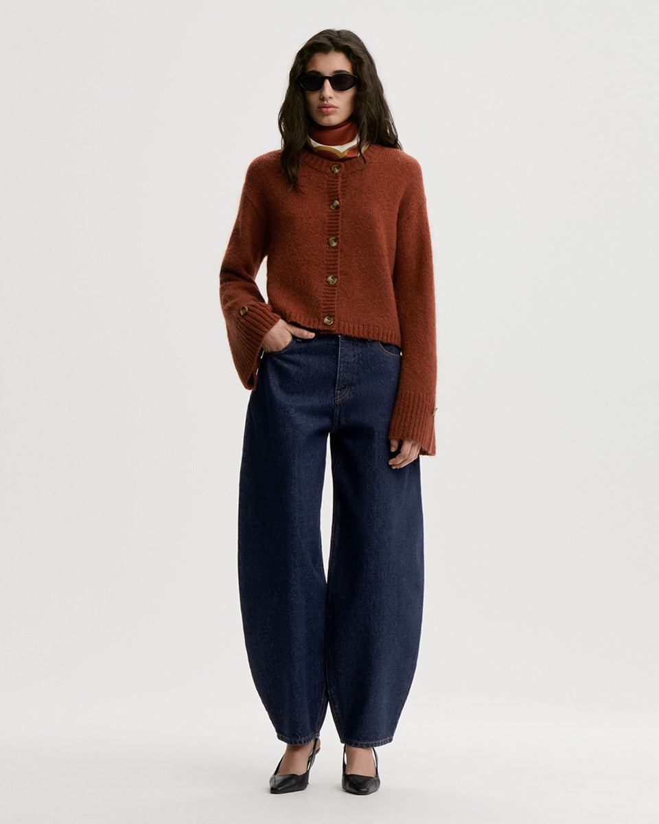 Krótki, swobodnie układający się sweter Cierrou Soft By Malene Birger Spiced Berry w rudym odcieniu. Ma okrągły dekolt i długie, lekko rozszerzane rękawy. Zapinany na rząd guzików. Dodatkowe, mniejsze guziki umieszczono również jako subtelny akcent na mankietach rękawów. Wykończony ściągaczami. Wykonany z ciepłej mieszanki wełny i moheru.
-Rozszerzane rękawy
-Dzianina z wełną i moherem
-Zamów sweter w swoim standardowym rozmiarze 