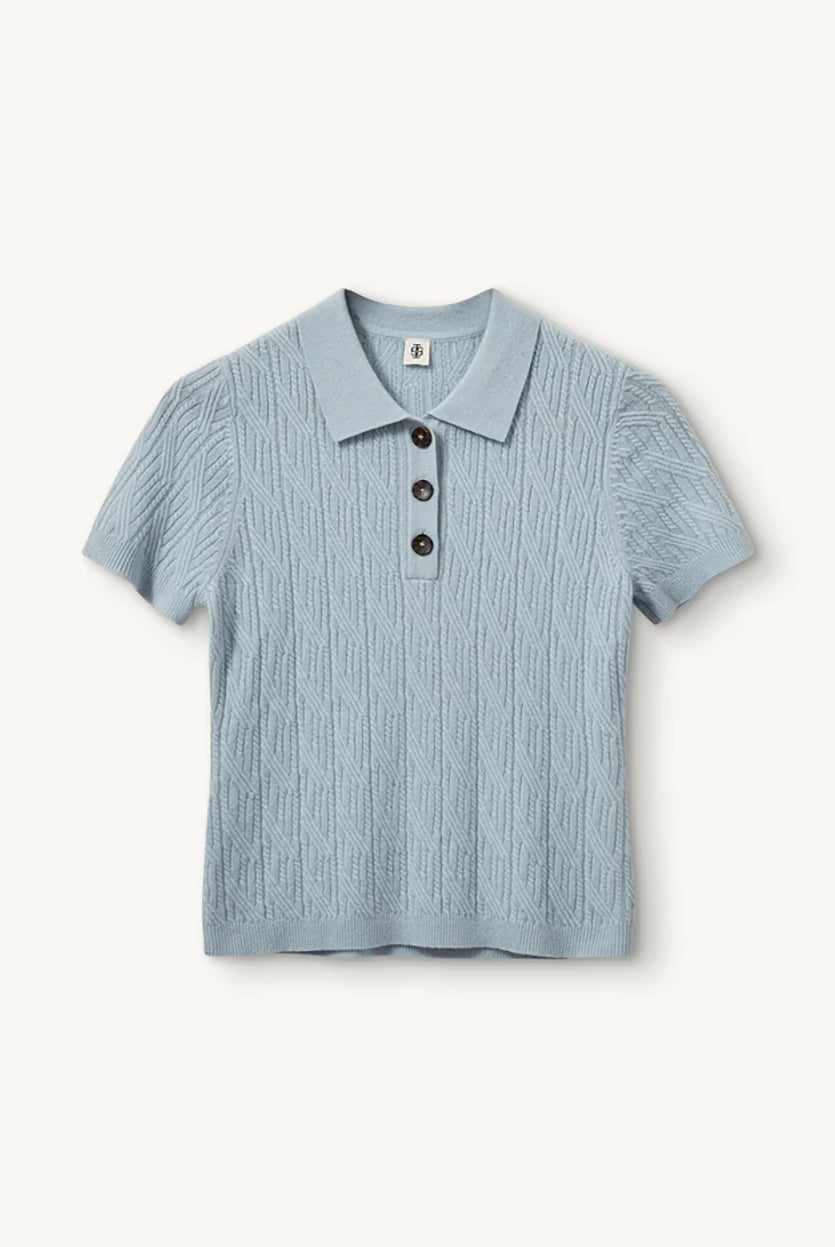 Miękka, dzianinowa, krótka koszulka polo Como Cable Light Blue w warkoczowy splot z klasycznym kołnierzykiem i krótkim rękawem. Przy kołnierzyku posiada trzy ciemne, kontrastujące guziki. Wykończona ściągaczami. Wykonana z mieszanki wełny i kaszmiru. Zestaw ją z jeansami lub lnianą spódnicą midi, co stworzy bardziej kobiecą, letnią stylizację.
-Warkoczykowy splot
-Tkanina z wełną i kaszmirem
-Zamów w swoim standardowym rozmiarze