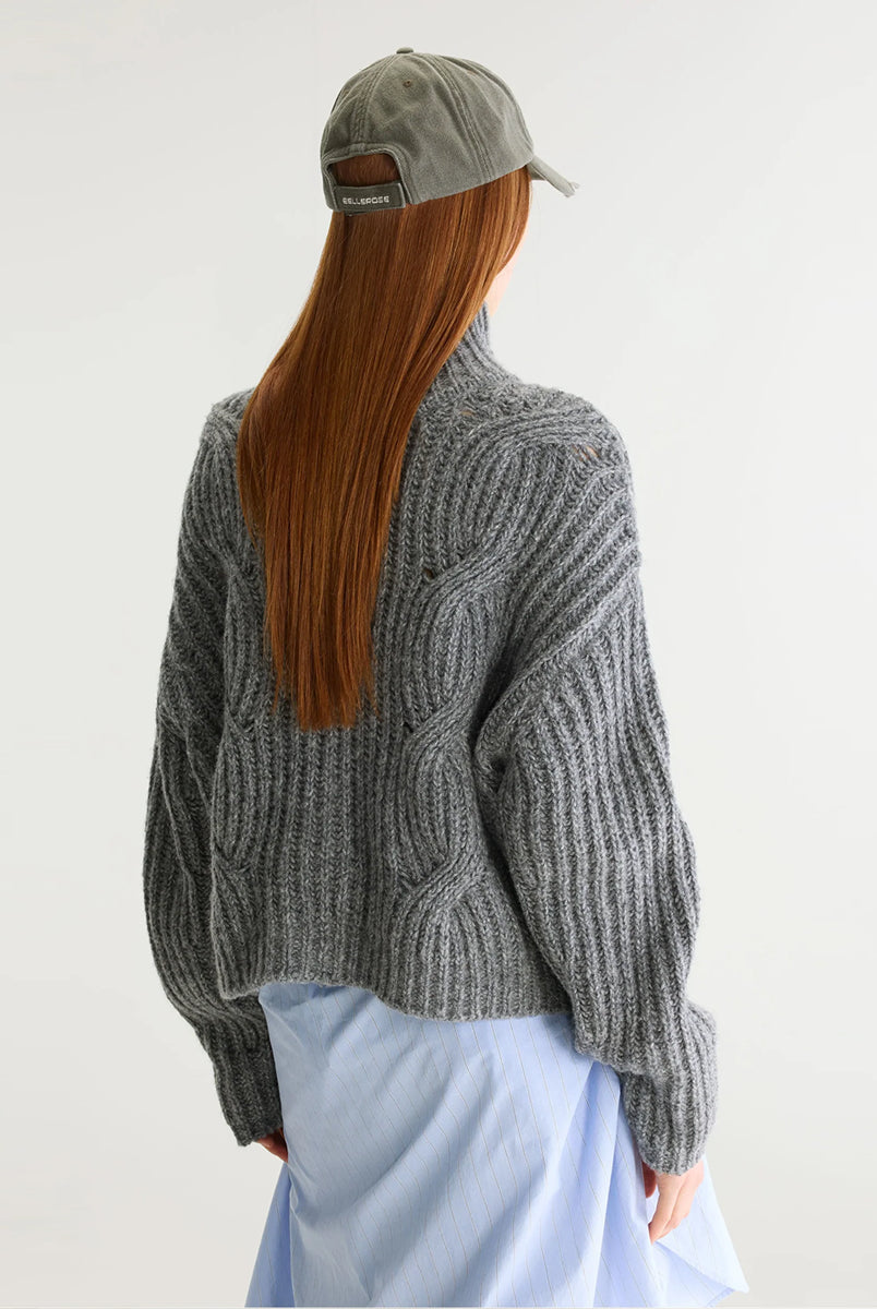 Szary sweter z golfem Deteo Mid Grey marki Bellerose o kroju oversize. Wykonany ściegiem typu "full cardigan", wyróżnia się bardzo grubym splotem ściągaczowym oraz dużymi wzorami warkoczowymi korpusie i rękawach.
-Krój oversize: celowo powiększony fason zapewniający obszerną, luźną sylwetkę
-Golf
-Warkoczowy splot 
