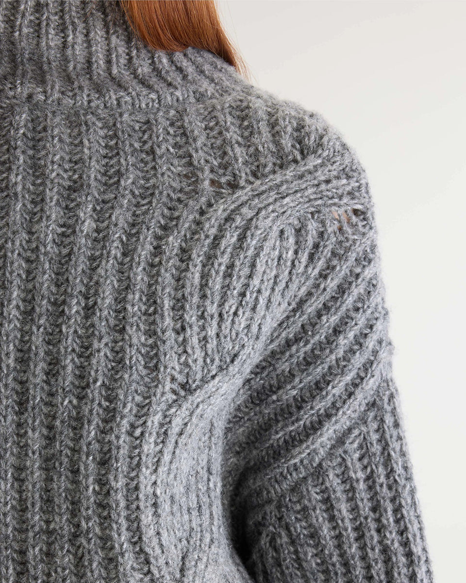 Szary sweter z golfem Deteo Mid Grey marki Bellerose o kroju oversize. Wykonany ściegiem typu "full cardigan", wyróżnia się bardzo grubym splotem ściągaczowym oraz dużymi wzorami warkoczowymi korpusie i rękawach.
-Krój oversize: celowo powiększony fason zapewniający obszerną, luźną sylwetkę
-Golf
-Warkoczowy splot 