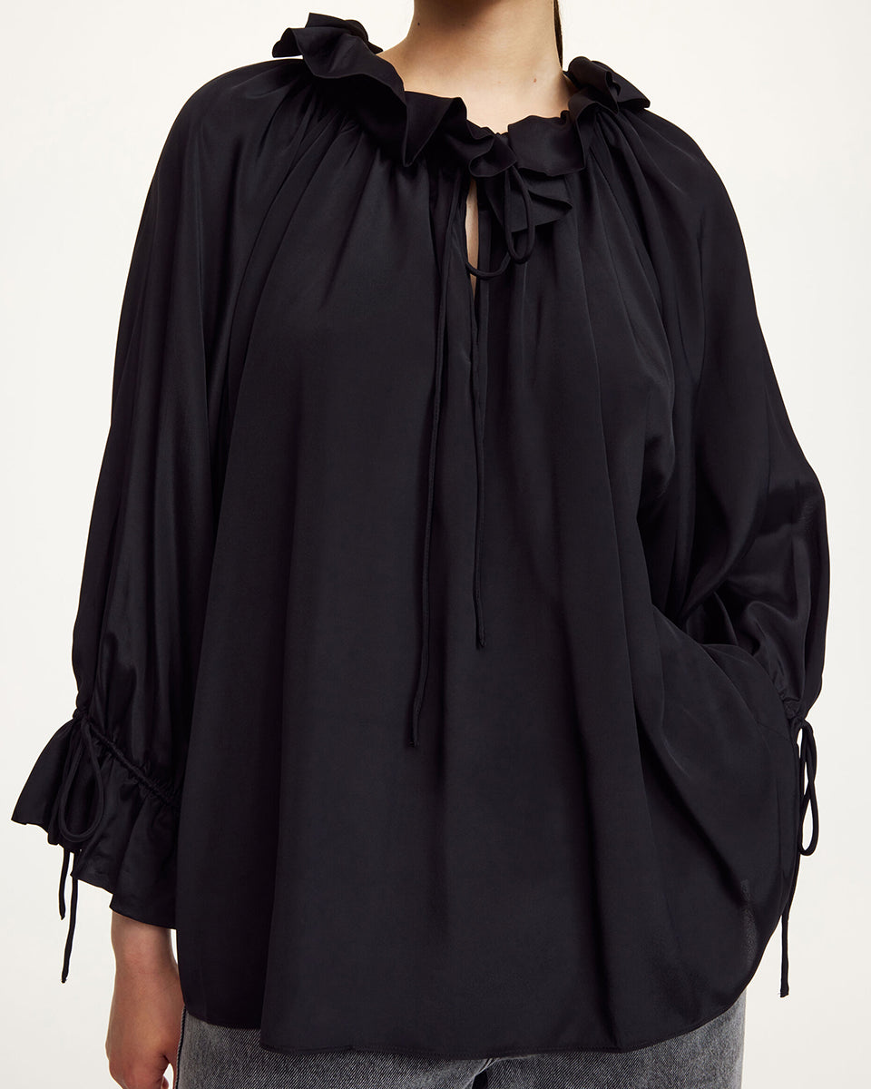 Oversizowa, lekka bluzka Dicte Black By Malene Birger z szerokimi rękawami 7/8, które zakończone są efektowną falbaną oraz ściągaczem, co tworzy delikatny efekt "bombki". Posiada kołnierz ze stójką z gęstym marszczeniem i falbaną. Dekolt jest rozcięty i posiada troczki, które można związać lub pozostawić luźno. Dół wykończony na prosto pozwala nosić bluzkę zarówno wypuszczoną, jak i luźno wpuszczoną w spodnie.
-Zamów w swoim standardowym rozmiarze