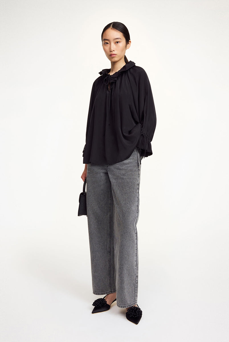 Oversizowa, lekka bluzka Dicte Black By Malene Birger z szerokimi rękawami 7/8, które zakończone są efektowną falbaną oraz ściągaczem, co tworzy delikatny efekt "bombki". Posiada kołnierz ze stójką z gęstym marszczeniem i falbaną. Dekolt jest rozcięty i posiada troczki, które można związać lub pozostawić luźno. Dół wykończony na prosto pozwala nosić bluzkę zarówno wypuszczoną, jak i luźno wpuszczoną w spodnie.
-Zamów w swoim standardowym rozmiarze