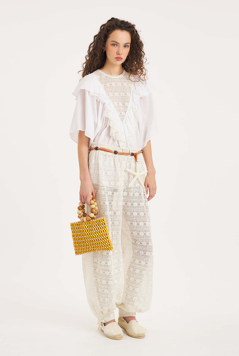 Luźna, biała bluzka Dolly White marki Antik Batik o swobodnym kroju, wyróżniającą się mocno romantycznym stylem boho. Z przodu jak i z tyłu posiada duży, ażurowy panel z misternej koronki o geometryczno- kwiatowym wzorze, który układa się w kształt litery V. Koronkowy dekolt zakończony jest szerokimi falbanami, które płynnie przechodzą w luźne, motylkowe rękawy o długości do łokcia. Z tyłu bluzka posiada subtelne rozcięcie w łezkę zapinane na guzik.
-Swobodny, luźny fason
-Falbany
-Koronka
-Zamów