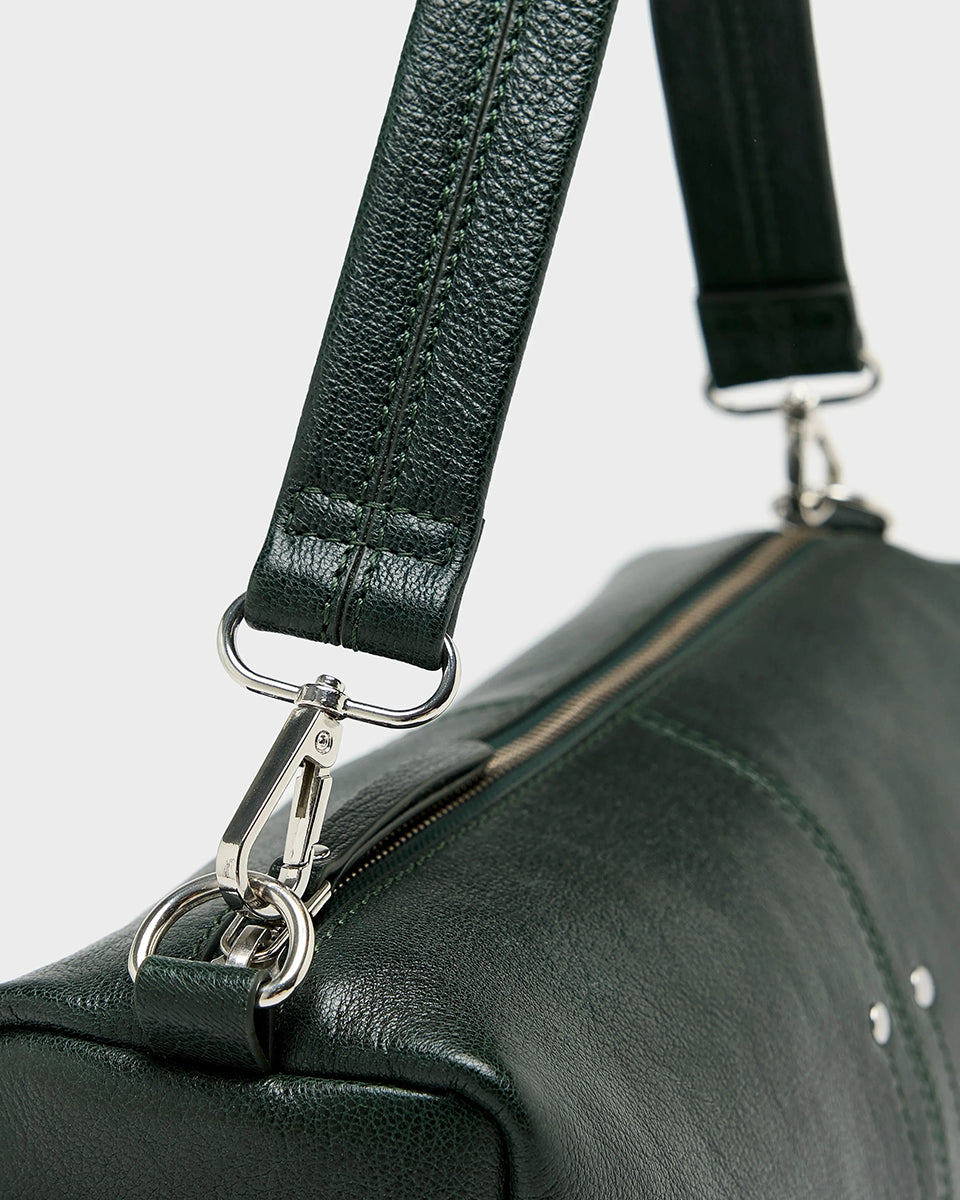 Torebka typu crossbody Duol Bottle Green marki BELLEROSE z teksturowanej, butelkowo-zielonej skóry koziej. Posiada regulowany, odpinany, beżowy pasek bawełniany oraz krótki, skórzany uchwyt. Zapinana na zamek błyskawiczny. Z przodu ma metalowe logo marki. Posiada wewnętrzną kieszeń główną, wewnętrzną kieszeń naszywaną oraz zewnętrzną kieszonkę boczną. 
