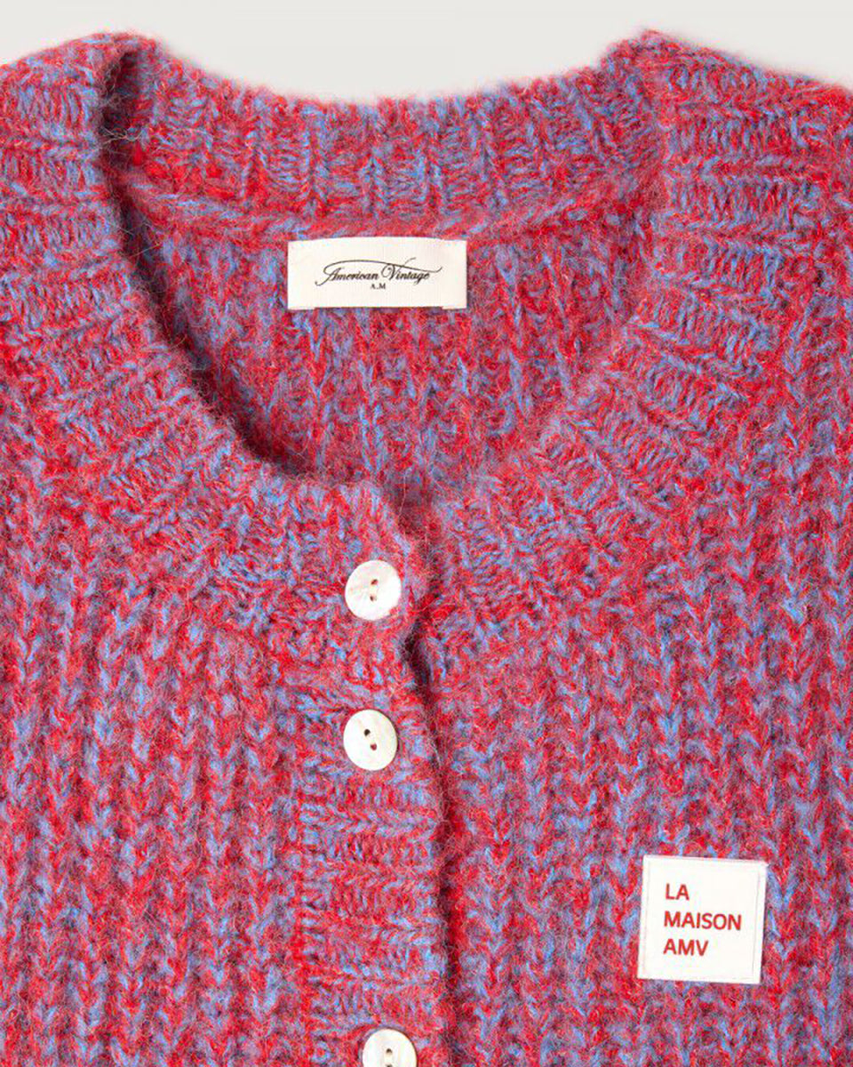 Krótki kardigan EAST19 Chili Red marki American Vintage bez rękawów, z okrągłym dekoltem i zapięciem na guziki. Posiada naszywkę z logo na piersi. Wyjątkowości i nowoczesności dodaje mu efekt uzyskany przez połączenie dwóch kontrastujących nici. Wykonany z puszystej dzianiny z alpaką i wełną. Niezbędny sweter, który można nosić samodzielnie lub na golf. 