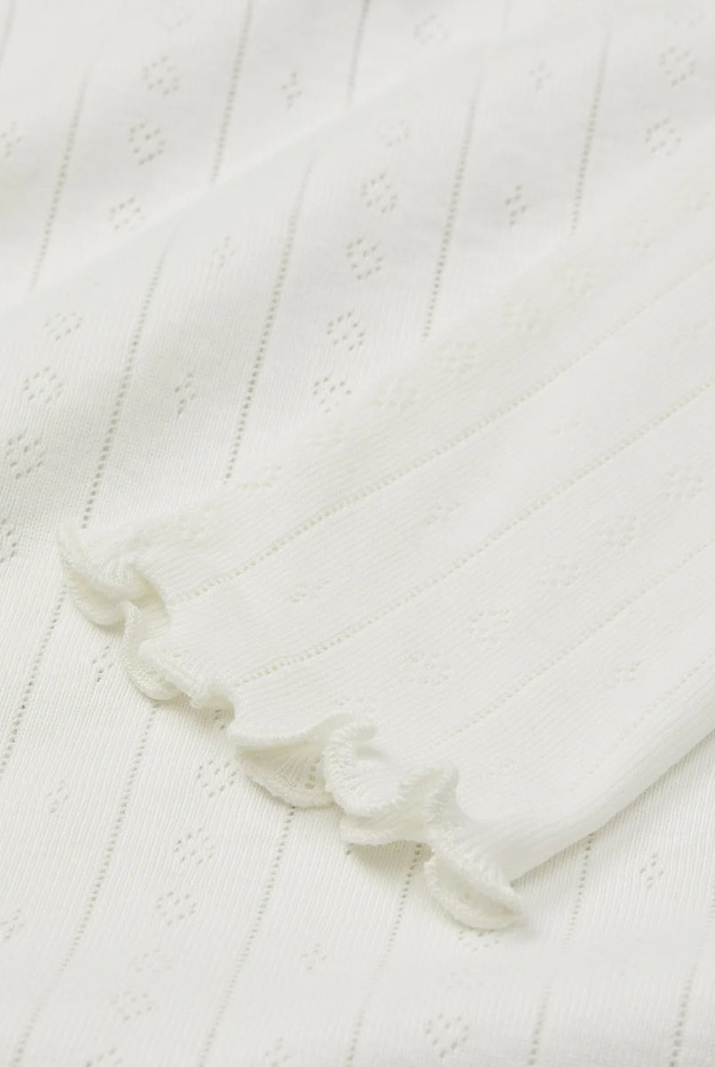 Cienki, biały longsleeve o przylegającym fasonie Edie SKALL. Posiada okrągły dekolt i wąskie, długie rękawy. Wykonany z miękkiej, bawełnianej tkaniny z delikatnym, ażurowym wzorem. U dołu i przy nadgarstkach wykończony falbanką.
-Przylegający fason
-100% bawełna organiczna
-Zamów bluzkę w swoim normalnym rozmiarze
