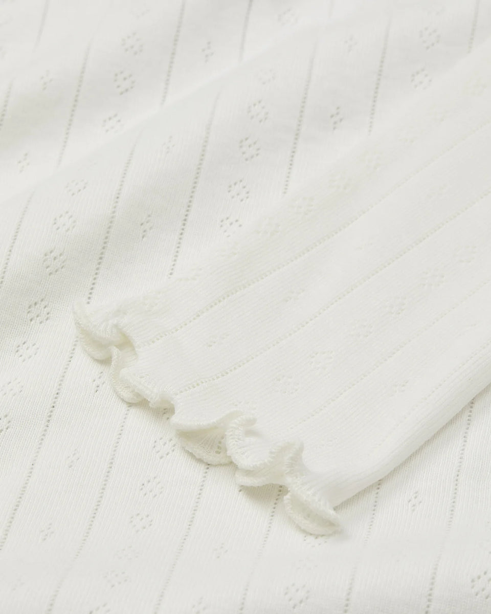 Cienki, biały longsleeve o przylegającym fasonie Edie SKALL. Posiada okrągły dekolt i wąskie, długie rękawy. Wykonany z miękkiej, bawełnianej tkaniny z delikatnym, ażurowym wzorem. U dołu i przy nadgarstkach wykończony falbanką.
-Przylegający fason
-100% bawełna organiczna
-Zamów bluzkę w swoim normalnym rozmiarze
