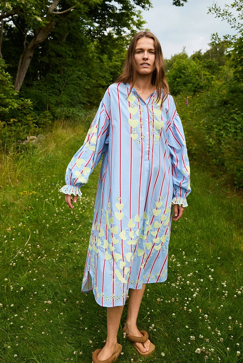 Haftowana, oversizowa sukienka maxi w czerwono-różowe paski Elisabeth Bluebell Stripes SISSEL EDELBO z długimi, szerokimi rękawami i opadającymi ramionami. Mankiety rękawów są zwężane i wykończone uroczą falbanką. Sukienka ma okrągły dekolt. Na dekolcie zapinana jest za pomocą drobnych guzików z masy perłowej. Wykonana jest ze zwiewnej bawełny organicznej z haftem z motywem serc. Posiada długość przed kostki.
-ONE SIZE
-Oversize
-100% bawełna organiczna