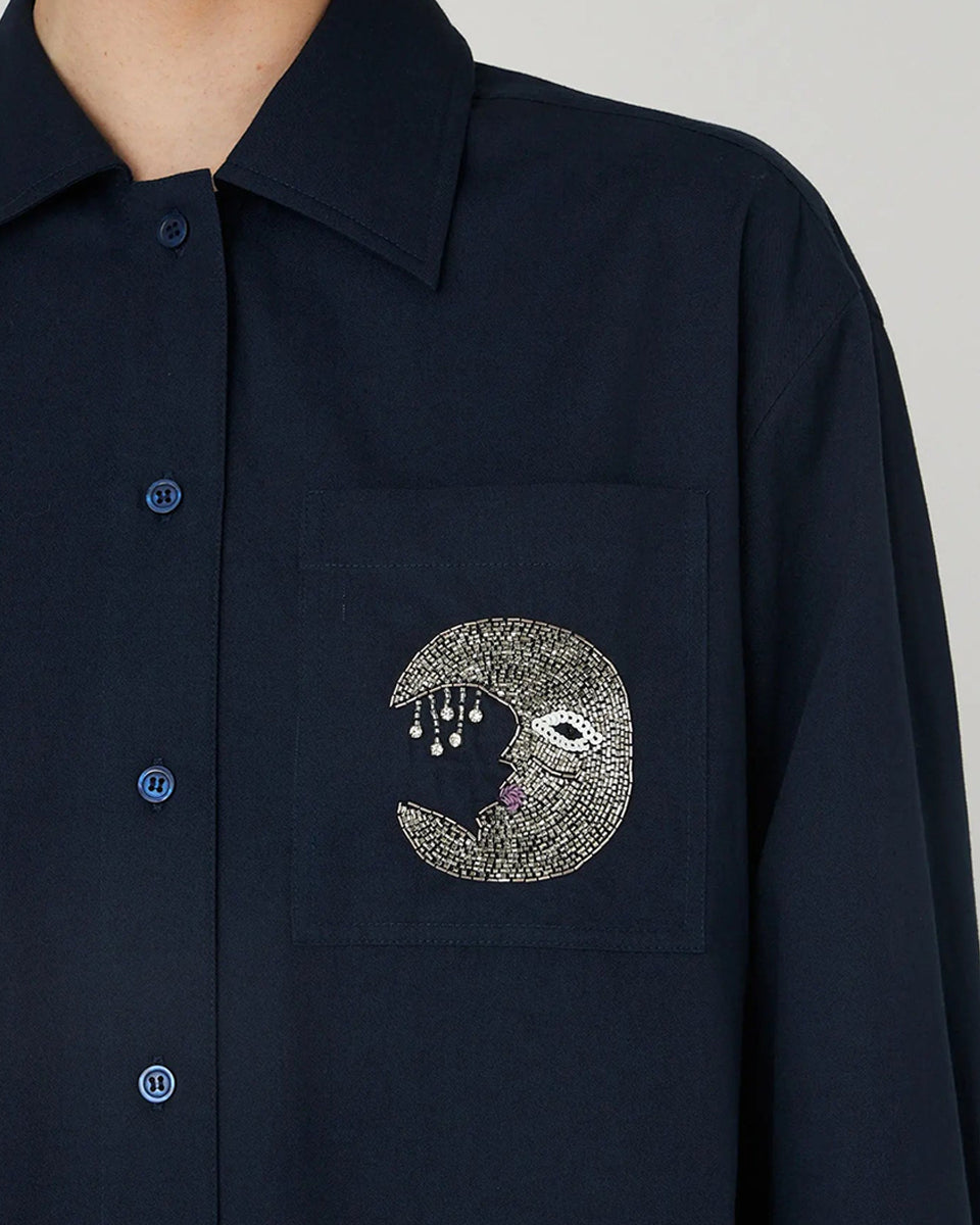 Luźna, granatowa koszula Embellished Moon Navy marki STELLA NOVA z długimi rękawami i mankietem. Ma klasyczny kołnierzyk i zapięcie na guziki z przodu. Na lewej piersi posiada kieszeń z wyhaftowanym księżycem. 