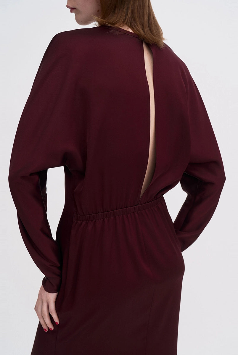 Minimalistyczna, luźna, elegancka sukienka midi Filippa K z okrągłym dekoltem i długimi rękawami rozszerzanymi pod pachami z guzikami przy mankietach. Na plecach posiada długie, wąskie rozcięcie. Z tyłu przy szyi zapinana na jeden guzik. Lekko zwężana w talii. Z tyłu w pasie ma elastyczną gumkę.