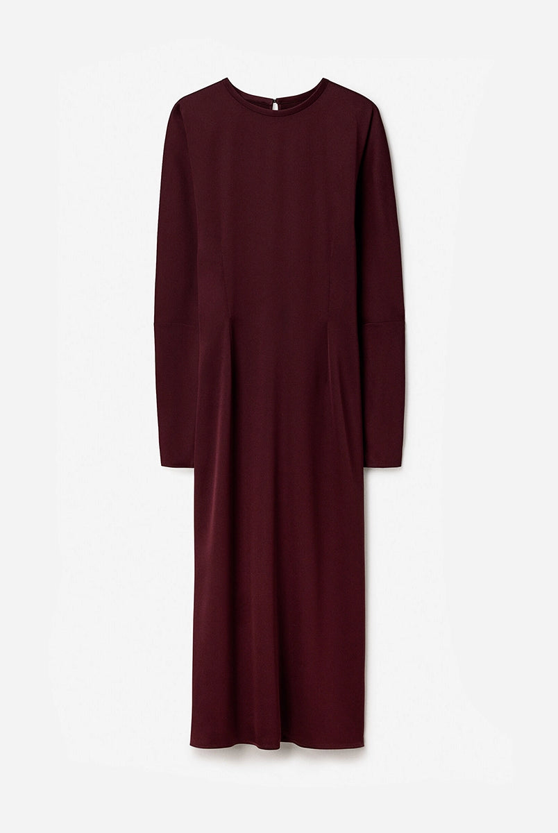 Minimalistyczna, luźna, elegancka sukienka midi Filippa K z okrągłym dekoltem i długimi rękawami rozszerzanymi pod pachami z guzikami przy mankietach. Na plecach posiada długie, wąskie rozcięcie. Z tyłu przy szyi zapinana na jeden guzik. Lekko zwężana w talii. Z tyłu w pasie ma elastyczną gumkę.