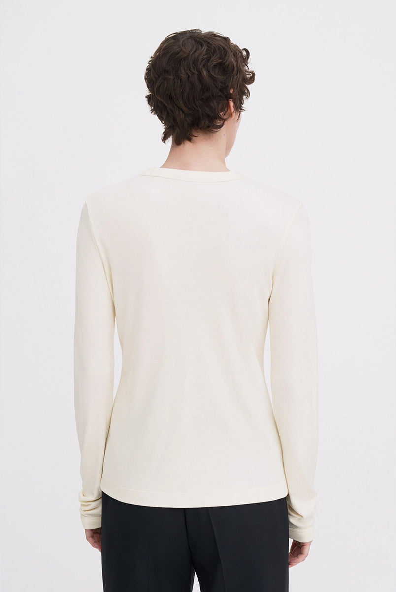 Luźny, minimalistyczny longsleeve Filippa K z okrągłym dekoltem i długimi rękawami. Top ma prosty krój. Jest wykonany z bardzo miękkiej i lejącej tkaniny z prążkowaną fakturą.