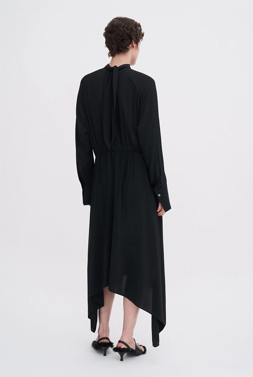 Minimalistyczna, luźna, elegancka sukienka midi Filippa K z wysokim dekoltem w formie golfu i wiązaniem z tyłu przy szyi. Sukienka ma długie rękawy zakończone mankietami oraz efektowne, wąskie rozcięcie na plecach. Z przodu marszczona przy dekolcie i i talii. U dołu wykończona asymetrycznie