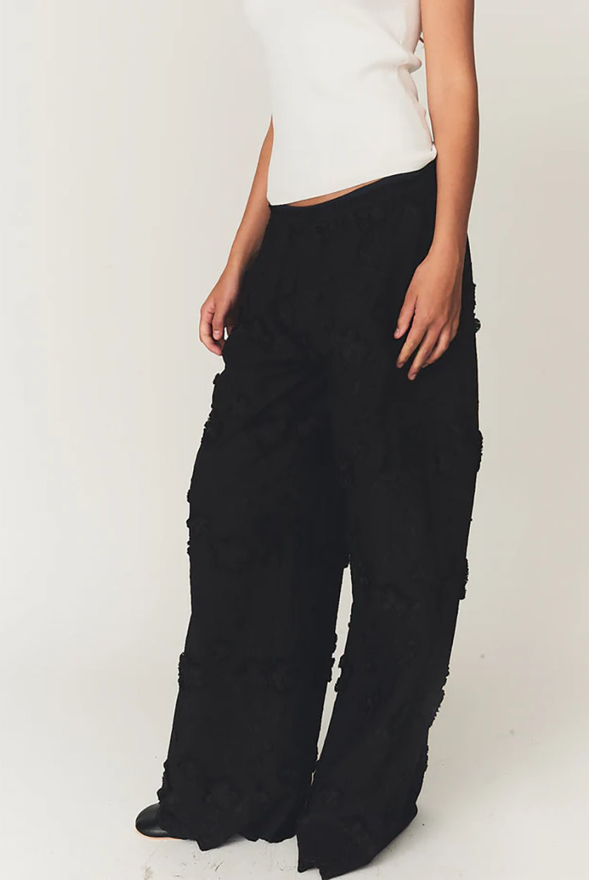 Luźne, proste, czarne spodnie Fleur Black marki The Garment z długimi, szerokimi nogawkami i elastyczną talią z gumką w pasie. Na całej powierzchni naszyte są wypukłe, kwiatowe aplikacje 3D. Dół nogawek wykończony jest naturalnym, falistym brzegiem koronki. Te spodnie to idealna alternatywa dla klasycznej sukienki wieczorowej.
-Luźny krój typu wide-leg
-Wypukłe, kwiatowe aplikacje
-Zamów spodnie w swoim normalnym rozmiarze