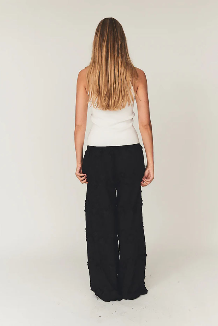 Luźne, proste, czarne spodnie Fleur Black marki The Garment z długimi, szerokimi nogawkami i elastyczną talią z gumką w pasie. Na całej powierzchni naszyte są wypukłe, kwiatowe aplikacje 3D. Dół nogawek wykończony jest naturalnym, falistym brzegiem koronki. Te spodnie to idealna alternatywa dla klasycznej sukienki wieczorowej.
-Luźny krój typu wide-leg
-Wypukłe, kwiatowe aplikacje
-Zamów spodnie w swoim normalnym rozmiarze