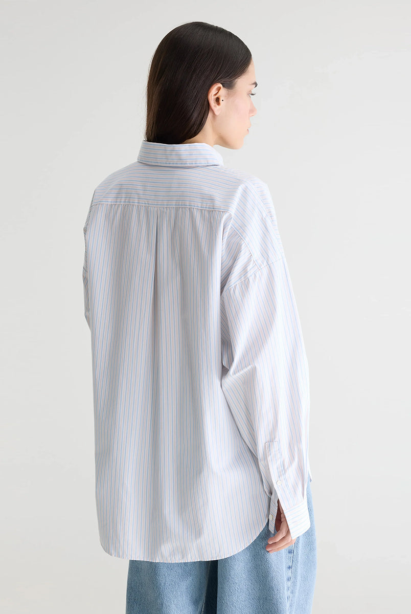 Oversizowa koszula Giorgia Stripe-A marki BELLEROSE z kołnierzykiem, obniżonymi ramionami i naszytą kieszenią na piersi. Posiada długie rękawy z mankietami zapinanymi na guziki. Wykonana z białej, bawełnianej popeliny w jasnoniebieskie i różowe paski. Zapinana na guziki.
-Luźny krój. Wybierz swój zwykły rozmiar lub mniejszy, jeśli chcesz uzyskać bardziej dopasowany look.