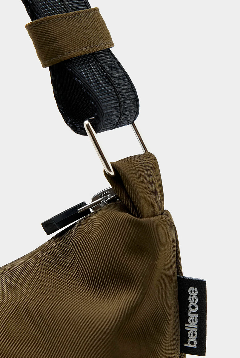 Mała torba typu sling w kolorze khaki Hane Carbone marki Bellerose o miękkiej, zaokrąglonej konstrukcji. Model wyposażony w zapięcie na zamek błyskawiczny; szeroki, regulowany pasek z taśmy, srebrne okucia i wewnętrzną kieszeń. Posiada podszewkę z lekkiego materiału technicznego. 