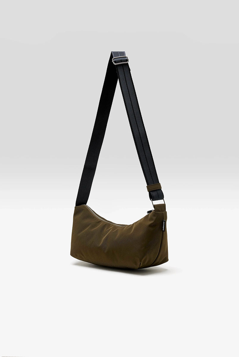 Mała torba typu sling w kolorze khaki Hane Carbone marki Bellerose o miękkiej, zaokrąglonej konstrukcji. Model wyposażony w zapięcie na zamek błyskawiczny; szeroki, regulowany pasek z taśmy, srebrne okucia i wewnętrzną kieszeń. Posiada podszewkę z lekkiego materiału technicznego. 