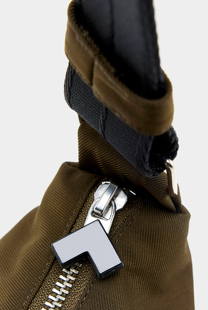Mała torba typu sling w kolorze khaki Hane Carbone marki Bellerose o miękkiej, zaokrąglonej konstrukcji. Model wyposażony w zapięcie na zamek błyskawiczny; szeroki, regulowany pasek z taśmy, srebrne okucia i wewnętrzną kieszeń. Posiada podszewkę z lekkiego materiału technicznego. 