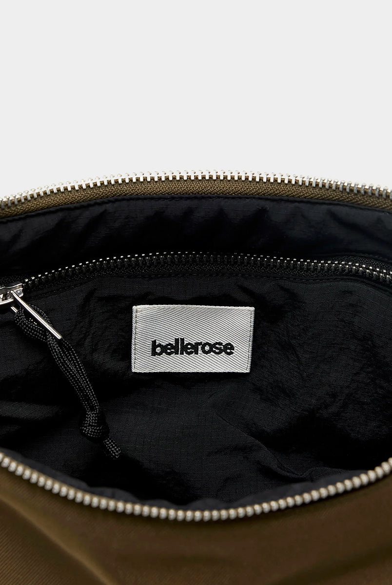 Mała torba typu sling w kolorze khaki Hane Carbone marki Bellerose o miękkiej, zaokrąglonej konstrukcji. Model wyposażony w zapięcie na zamek błyskawiczny; szeroki, regulowany pasek z taśmy, srebrne okucia i wewnętrzną kieszeń. Posiada podszewkę z lekkiego materiału technicznego. 