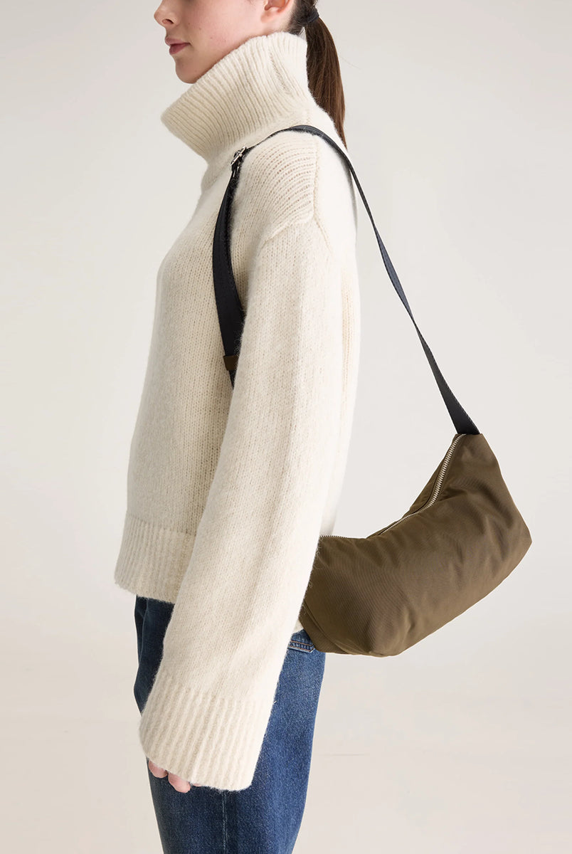 Mała torba typu sling w kolorze khaki Hane Carbone marki Bellerose o miękkiej, zaokrąglonej konstrukcji. Model wyposażony w zapięcie na zamek błyskawiczny; szeroki, regulowany pasek z taśmy, srebrne okucia i wewnętrzną kieszeń. Posiada podszewkę z lekkiego materiału technicznego. 