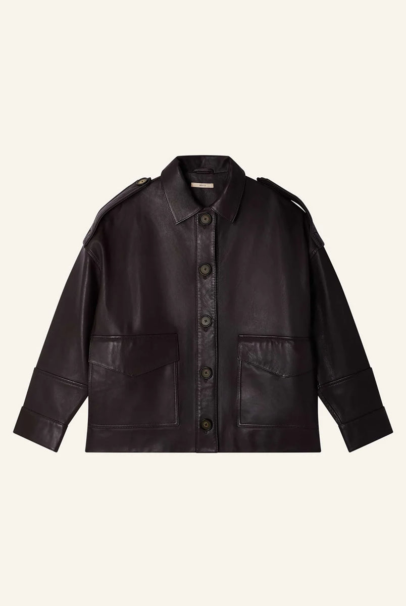 Brązowa, luźna kurtka Harriboyd Coffee Leather francuskiej marki Sessun w stylu klasycznej pilotki. Wykonana jest z gładkiej, ciemnobrązowej skóry o lekkim połysku. Z przodu zapinana jest na duże, czarne guziki, a po bogach ma duże naszywane kieszenie. Rękawy są długie, z mankietami zapinanymi na guzik. Tył kurtki jest prosty, z poziomym szwem przez plecy i elastycznym ściągaczem w dolnej części. 